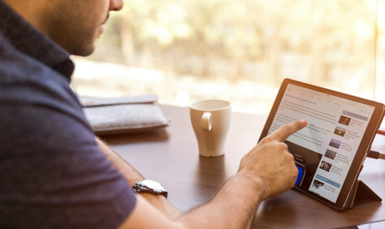 Un homme défilant du contenu sur l'écran de sa tablette avec son doigt